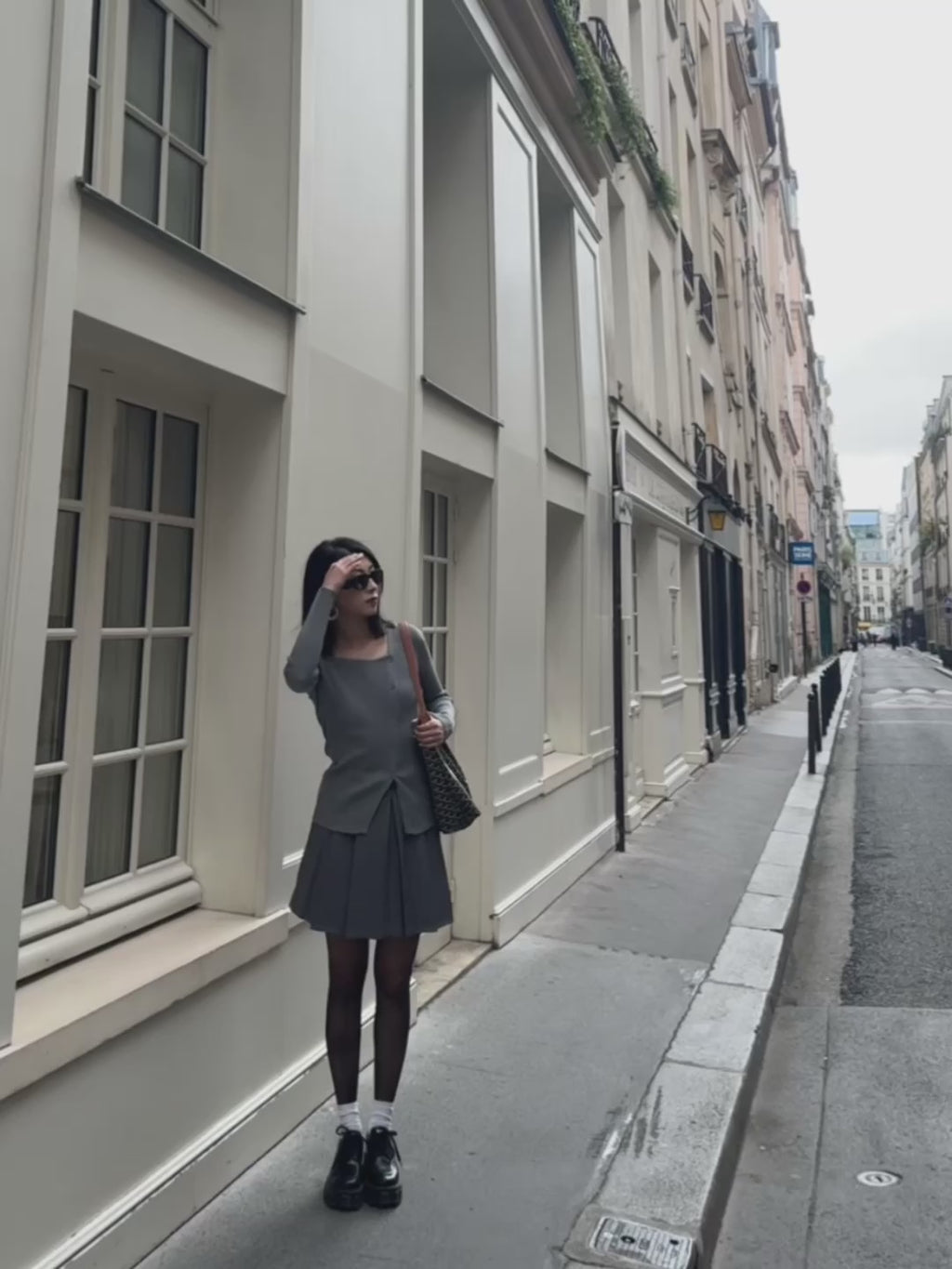 Jupe courte grise plissée en batavia avec une ceinture noire.